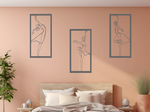 Metal wall art set featuring three minimalist ballerina silhouettes in various elegant dance poses, finished in Berry Grey Gloss powder coating, mounted on a light peach wall above a bed, adding a graceful and artistic touch to the bedroom