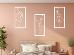 Metal wall art set featuring three minimalist ballerina silhouettes in various elegant dance poses, finished in Bright White Gloss powder coating, mounted on a light peach wall above a bed, adding a graceful and artistic touch to the bedroom.