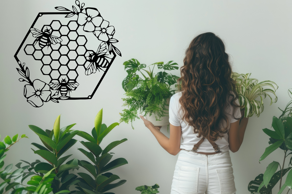 Metal wall art featuring three bees hovering over a floral honeycomb pattern, finished in Night Sky Matt Black powder coating, mounted on a light-colored wall, complementing indoor plants and creating a nature-inspired decor.