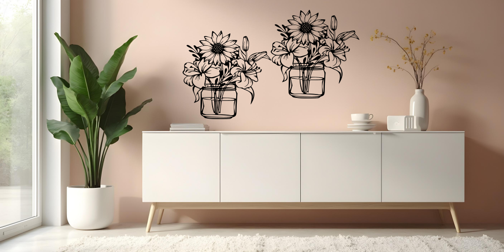 Metal wall art set featuring two jars filled with blooming flowers, including sunflowers and lilies, finished in Night Sky Matt Black powder coating, mounted on a soft pink wall above a modern white cabinet, creating a cheerful and nature-inspired interior decor.