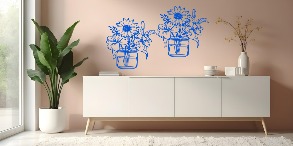 Metal wall art set featuring two jars filled with blooming flowers, including sunflowers and lilies, finished in Blaze Blue Gloss powder coating, mounted on a soft pink wall above a modern white cabinet, creating a cheerful and nature-inspired interior decor