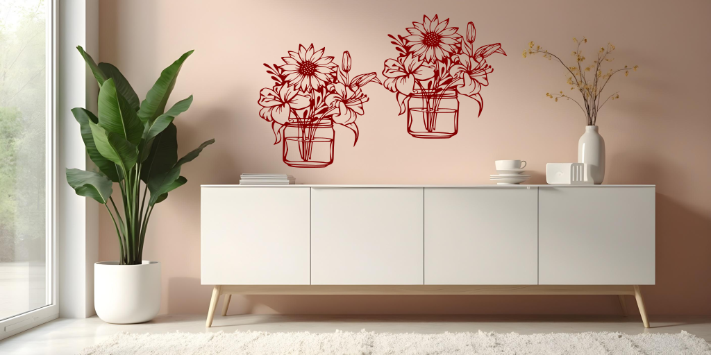 Metal wall art set featuring two jars filled with blooming flowers, including sunflowers and lilies, finished in Manor Red powder coating, mounted on a soft pink wall above a modern white cabinet, creating a cheerful and nature-inspired interior decor.