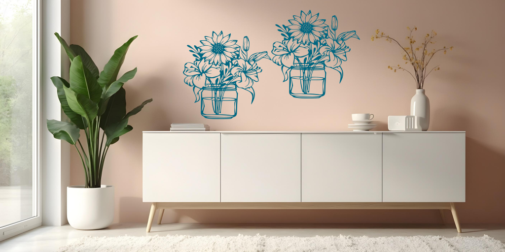 Metal wall art set featuring two jars filled with blooming flowers, including sunflowers and lilies, finished in Wedgwood Satin powder coating, mounted on a soft pink wall above a modern white cabinet, creating a cheerful and nature-inspired interior decor.