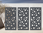 Metal privacy screen with a modern bubble pattern of varying circle sizes, finished in Berry Grey Gloss powder coating, displayed outdoors against a white wall, providing both privacy and an artistic element to the space.