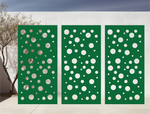 Metal privacy screen with a modern bubble pattern of varying circle sizes, finished in Mistletoe powder coating, displayed outdoors against a white wall, providing both privacy and an artistic element to the space.