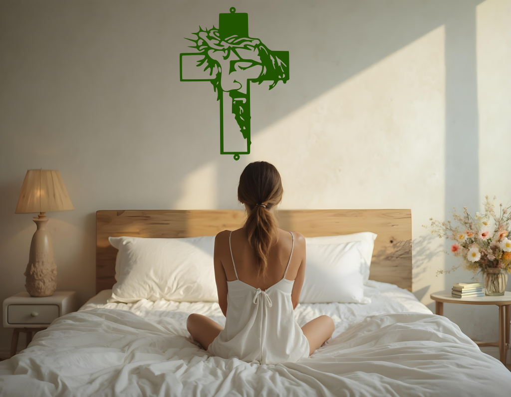 Metal wall art featuring a cross with a silhouette of Jesus wearing a crown of thorns, finished in Mistletoe powder coating, mounted on a light wall above a bed, adding a serene and spiritual element to the bedroom.