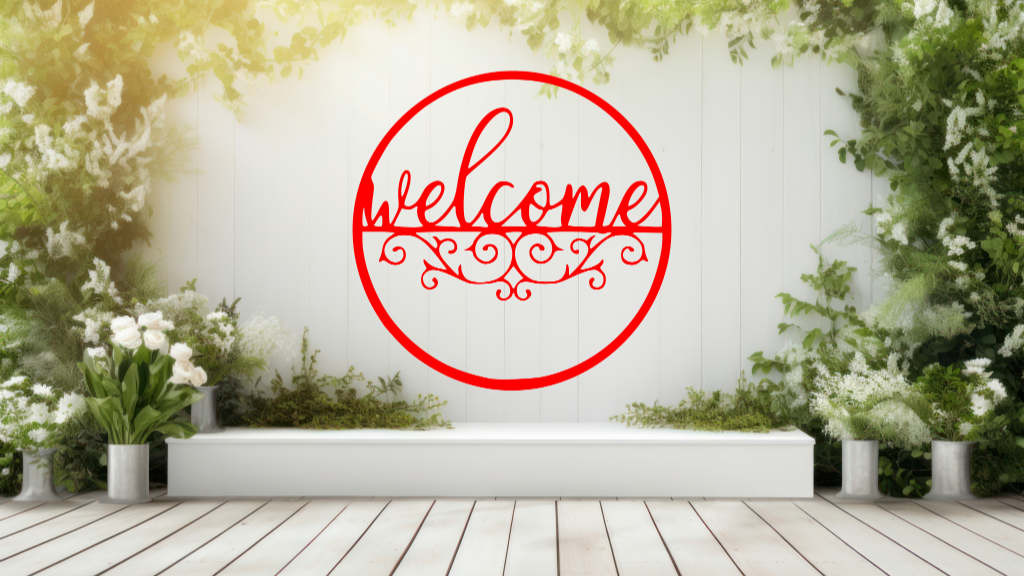 Metal wall art featuring a circular 'Welcome' sign with intricate scrollwork below the text, finished in Signal Red powder coating, mounted on a white fence surrounded by lush greenery, adding a charming and inviting touch to an outdoor garden space.