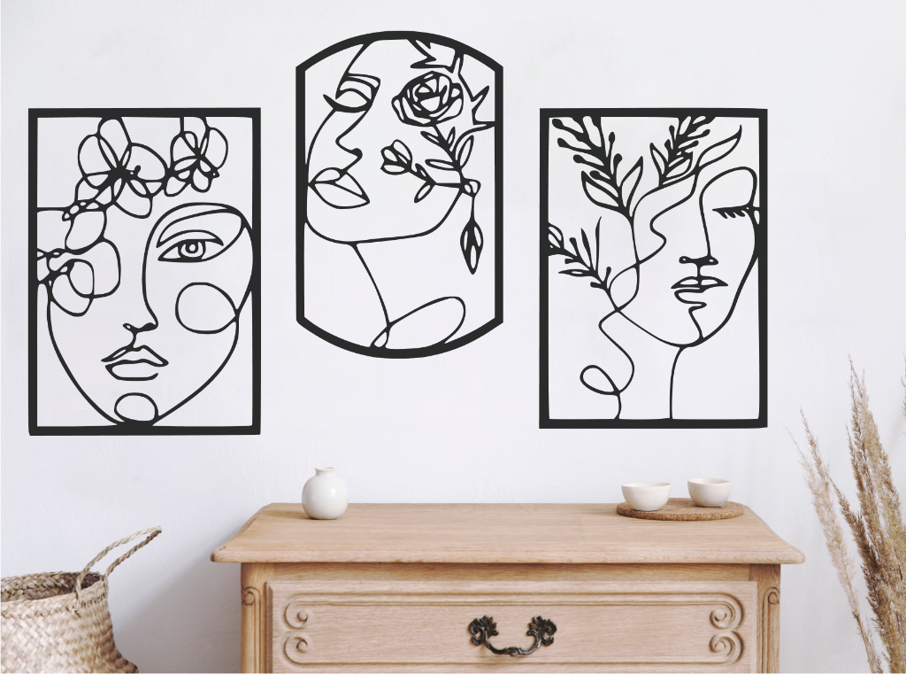 Set of three decorative metal wall art pieces, each featuring an abstract feminine face intertwined with floral elements, finished in Night Sky Matt Black powder coating. The artwork is displayed on a white wall above a wooden chest of drawers, adding a modern and artistic touch to the room.