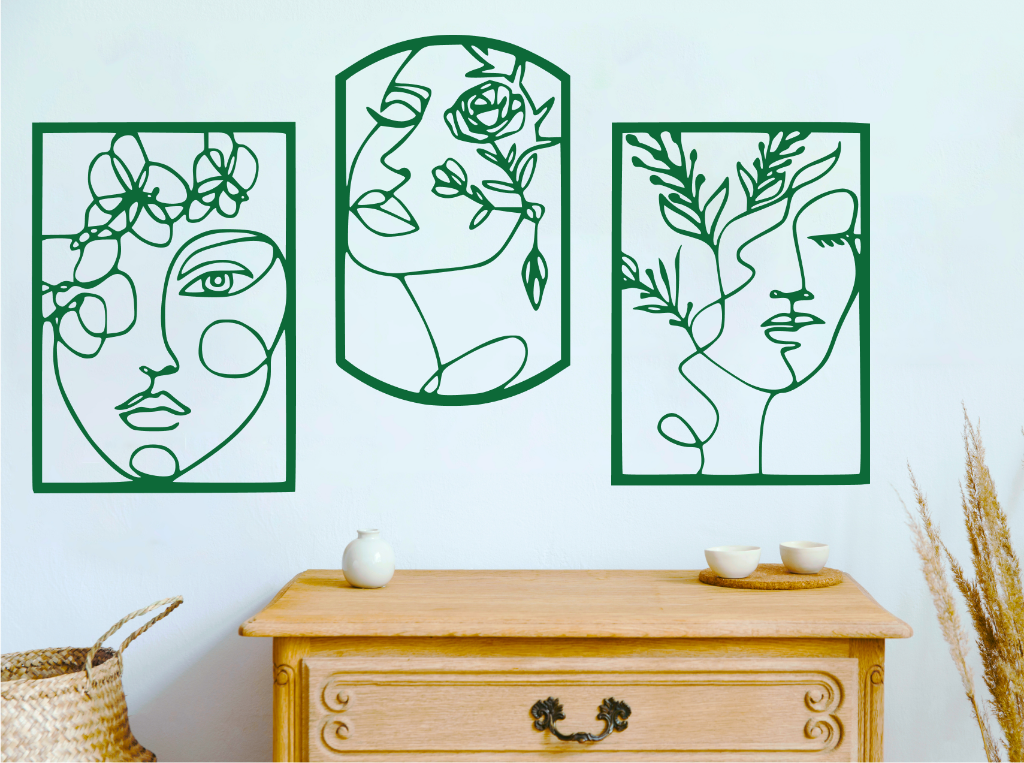 Set of three decorative metal wall art pieces, each featuring an abstract feminine face intertwined with floral elements, finished in Mistletoe powder coating. The artwork is displayed on a white wall above a wooden chest of drawers, adding a modern and artistic touch to the room.