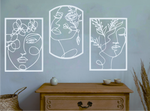 Set of three decorative metal wall art pieces, each featuring an abstract feminine face intertwined with floral elements, finished in Bright White Gloss powder coating. The artwork is displayed on a white wall above a wooden chest of drawers, adding a modern and artistic touch to the room.