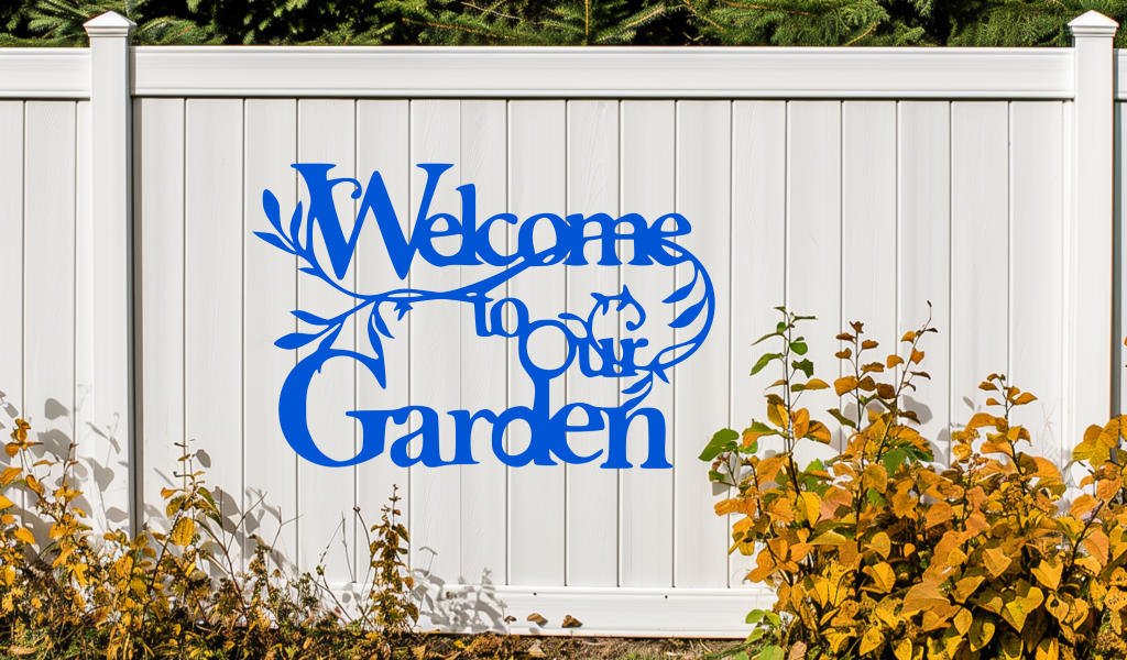 Metal wall art sign featuring the phrase 'Welcome to our Garden' with decorative branches and leaves integrated into the design, finished in Blaze Blue Gloss powder coating. The sign is mounted on a white fence, adding a welcoming touch to an outdoor garden space.