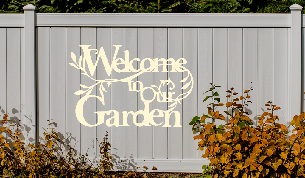 Metal wall art sign featuring the phrase 'Welcome to our Garden' with decorative branches and leaves integrated into the design, finished in Canola Cream powder coating. The sign is mounted on a white fence, adding a welcoming touch to an outdoor garden space