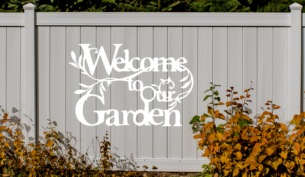 Metal wall art sign featuring the phrase 'Welcome to our Garden' with decorative branches and leaves integrated into the design, finished in Bright White Gloss powder coating. The sign is mounted on a white fence, adding a welcoming touch to an outdoor garden space.