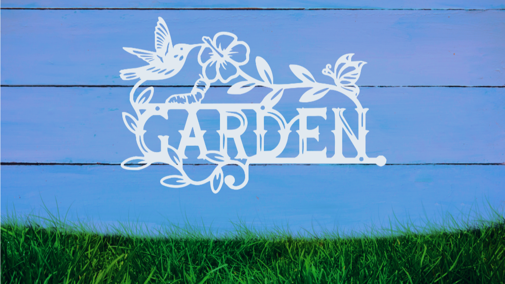 Metal wall art featuring the word 'GARDEN' with a decorative design of leaves, flowers, and a hummingbird, finished in Bright White Gloss powder coating, mounted on a white wooden wall above a patch of green grass, adding a welcoming and natural touch to outdoor garden spaces.