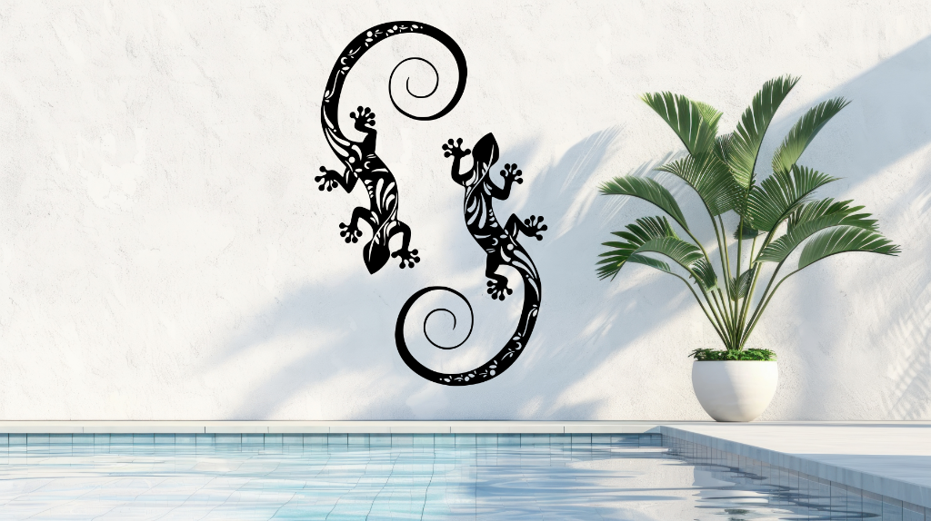 Metal wall art featuring two geckos with intricate detailing on their bodies, finished in Night Sky Matt Black powder coating, mounted on a light wall near a poolside, adding a tropical and playful touch to the outdoor space.