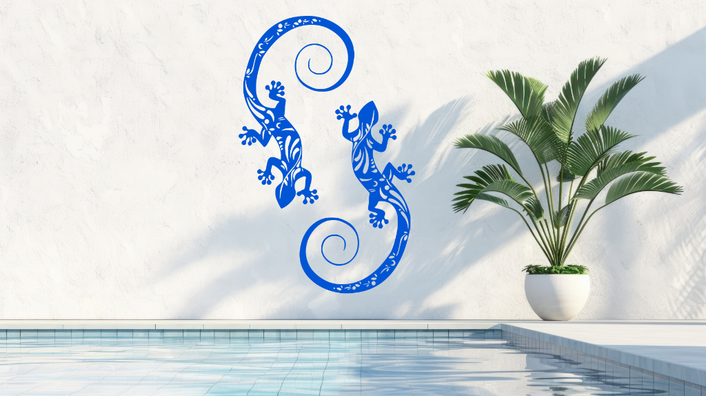 Metal wall art featuring two geckos with intricate detailing on their bodies, finished in Blaze Blue Gloss powder coating, mounted on a light wall near a poolside, adding a tropical and playful touch to the outdoor space.