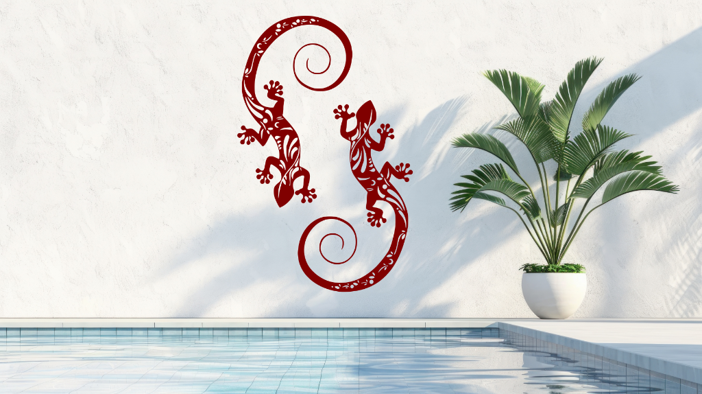 Metal wall art featuring two geckos with intricate detailing on their bodies, finished in Manor Red powder coating, mounted on a light wall near a poolside, adding a tropical and playful touch to the outdoor space.