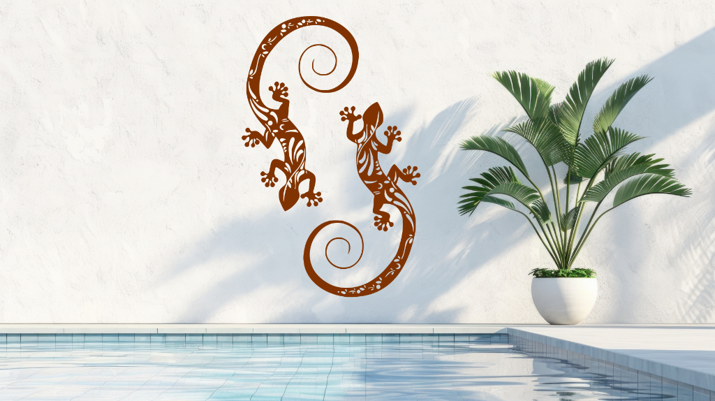 Metal wall art featuring two geckos with intricate detailing on their bodies, finished in Rust Patina powder coating, mounted on a light wall near a poolside, adding a tropical and playful touch to the outdoor space.