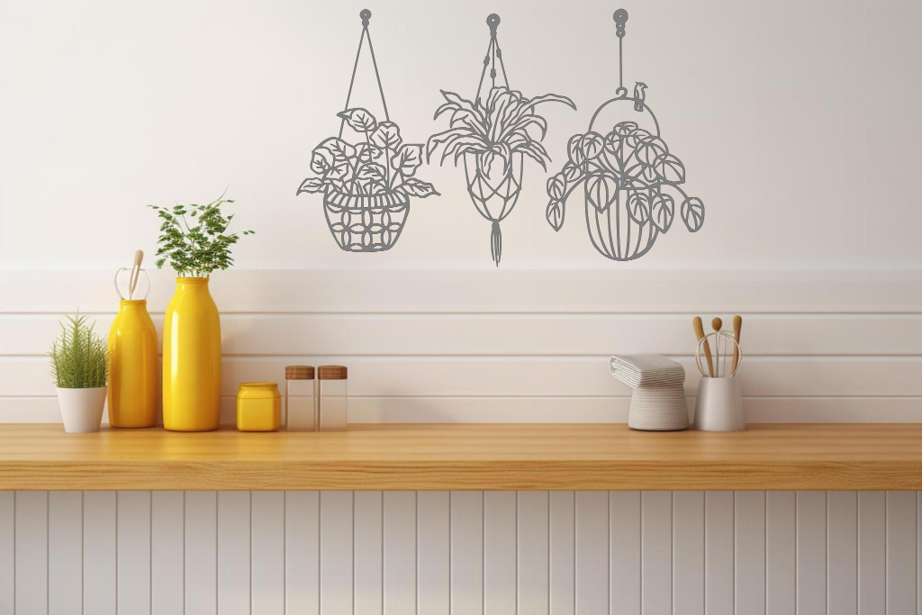 Metal wall art featuring three hanging planters with intricate plant designs, finished in Berry Grey Gloss powder coating, mounted on a kitchen wall. The piece brings a natural and modern aesthetic to the space, complementing the vibrant yellow decor elements on the counter below.