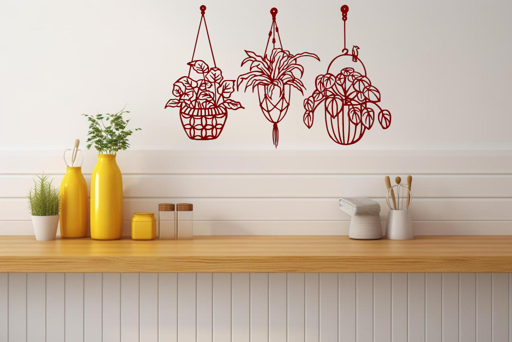 "Metal wall art featuring three hanging planters with intricate plant designs, finished in Manor Red powder coating, mounted on a kitchen wall. The piece brings a natural and modern aesthetic to the space, complementing the vibrant yellow decor elements on the counter below.