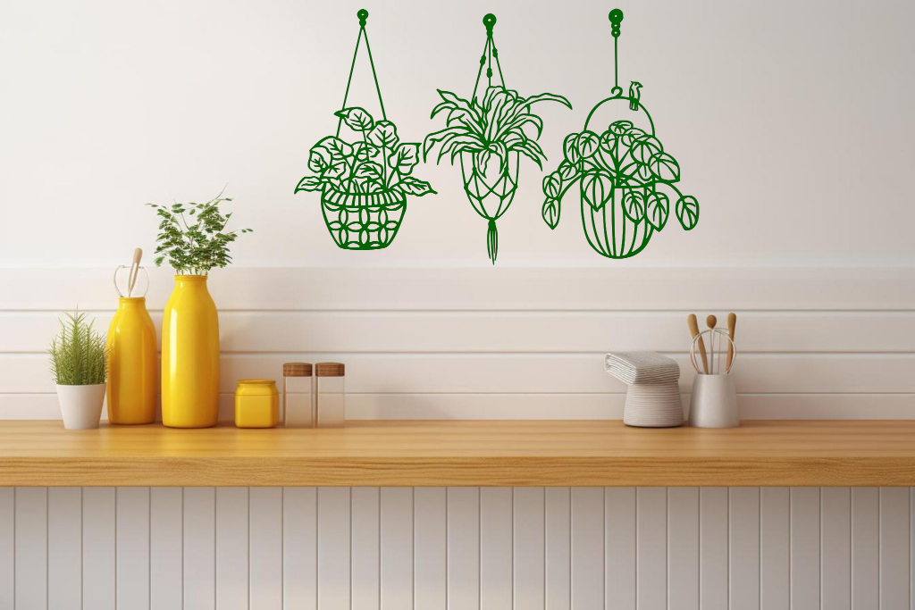 Metal wall art featuring three hanging planters with intricate plant designs, finished in Mistletoe powder coating, mounted on a kitchen wall. The piece brings a natural and modern aesthetic to the space, complementing the vibrant yellow decor elements on the counter below.