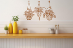 Metal wall art featuring three hanging planters with intricate plant designs, finished in Rust Patina powder coating, mounted on a kitchen wall. The piece brings a natural and modern aesthetic to the space, complementing the vibrant yellow decor elements on the counter below.