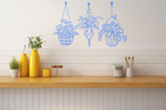 Metal wall art featuring three hanging planters with intricate plant designs, finished in Wedgwood Satin powder coating, mounted on a kitchen wall. The piece brings a natural and modern aesthetic to the space, complementing the vibrant yellow decor elements on the counter below.