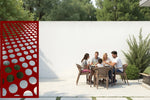 Bold privacy screen with circular cut-outs, coated in Manor Red powder, making a striking statement in outdoor environments while adding seclusion