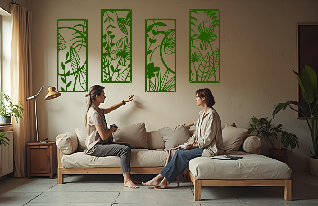 A four-piece metal wall art set from the 'Lush Escape Collection,' featuring intricate nature-inspired designs of leaves and flowers, finished in Mistletoe powder coating. The artwork is mounted on a living room wall above a neutral-toned sofa, adding a calming and organic touch to the space.