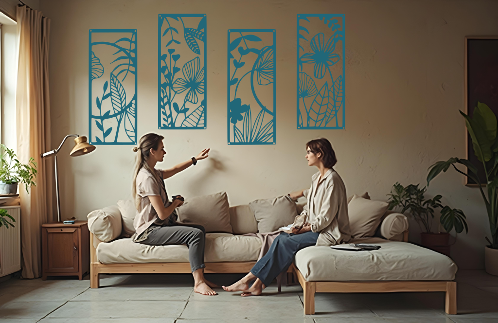 A four-piece metal wall art set from the 'Lush Escape Collection,' featuring intricate nature-inspired designs of leaves and flowers, finished in Wedgwood Satin powder coating. The artwork is mounted on a living room wall above a neutral-toned sofa, adding a calming and organic touch to the space.