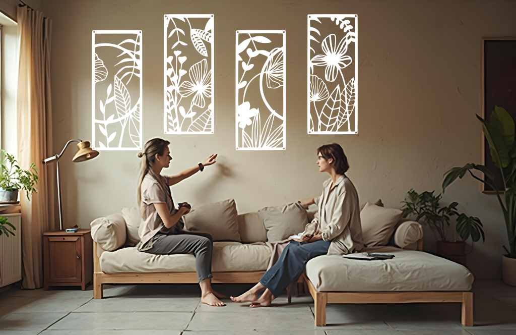 A four-piece metal wall art set from the 'Lush Escape Collection,' featuring intricate nature-inspired designs of leaves and flowers, finished in Bright White Gloss powder coating. The artwork is mounted on a living room wall above a neutral-toned sofa, adding a calming and organic touch to the space.