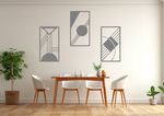 A three-piece minimalist metal wall art set from the 'Serenity in Simplicity' collection, featuring geometric designs of clean lines and abstract shapes, finished in Berry Grey Gloss powder coating. The artwork is mounted on a dining room wall above a simple wooden table with white chairs, creating a modern and calming aesthetic.