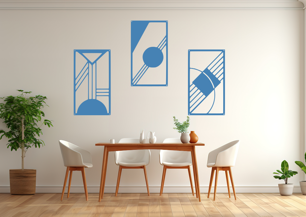 A three-piece minimalist metal wall art set from the 'Serenity in Simplicity' collection, featuring geometric designs of clean lines and abstract shapes, finished in Wedgwood Satin powder coating. The artwork is mounted on a dining room wall above a simple wooden table with white chairs, creating a modern and calming aesthetic.