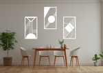 A three-piece minimalist metal wall art set from the 'Serenity in Simplicity' collection, featuring geometric designs of clean lines and abstract shapes, finished in Bright White Gloss powder coating. The artwork is mounted on a dining room wall above a simple wooden table with white chairs, creating a modern and calming aesthetic.