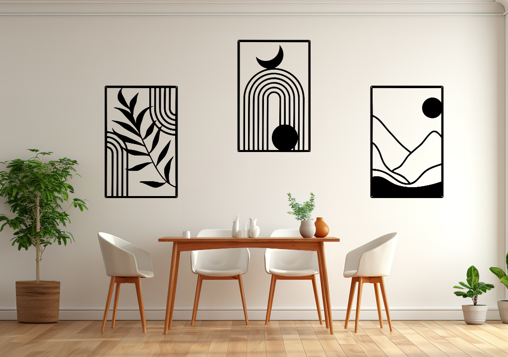 A three-piece minimalist geometric metal wall art set featuring abstract shapes, including a leaf design, a rainbow with moon and sun, and a mountain landscape, all finished in Night Sky Matt Black powder coating. The artwork is mounted on a dining room wall above a simple wooden table with white chairs, bringing a modern and artistic touch to the space