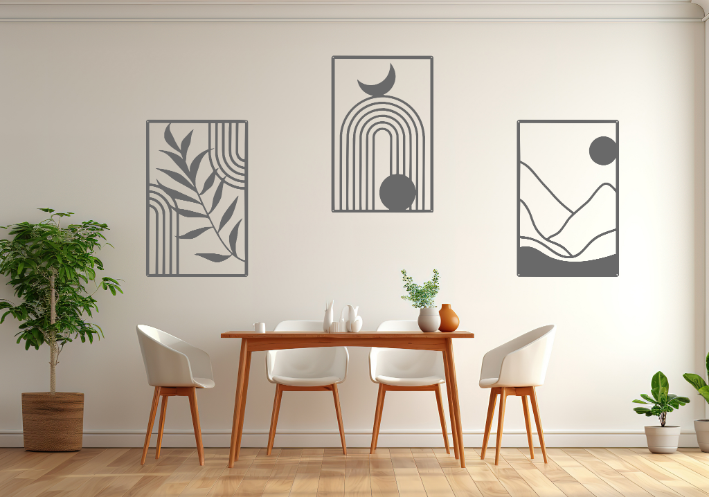 A three-piece minimalist geometric metal wall art set featuring abstract shapes, including a leaf design, a rainbow with moon and sun, and a mountain landscape, all finished in Berry Grey Gloss powder coating. The artwork is mounted on a dining room wall above a simple wooden table with white chairs, bringing a modern and artistic touch to the space.