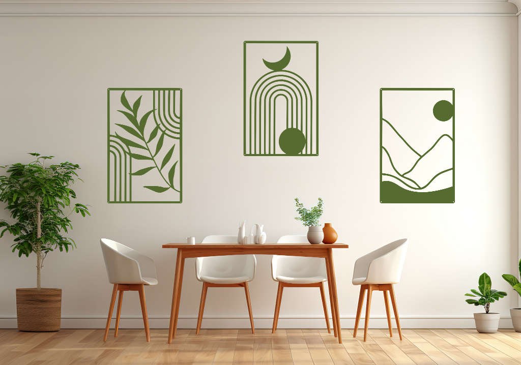 A three-piece minimalist geometric metal wall art set featuring abstract shapes, including a leaf design, a rainbow with moon and sun, and a mountain landscape, all finished in Mistletoe powder coating. The artwork is mounted on a dining room wall above a simple wooden table with white chairs, bringing a modern and artistic touch to the space.