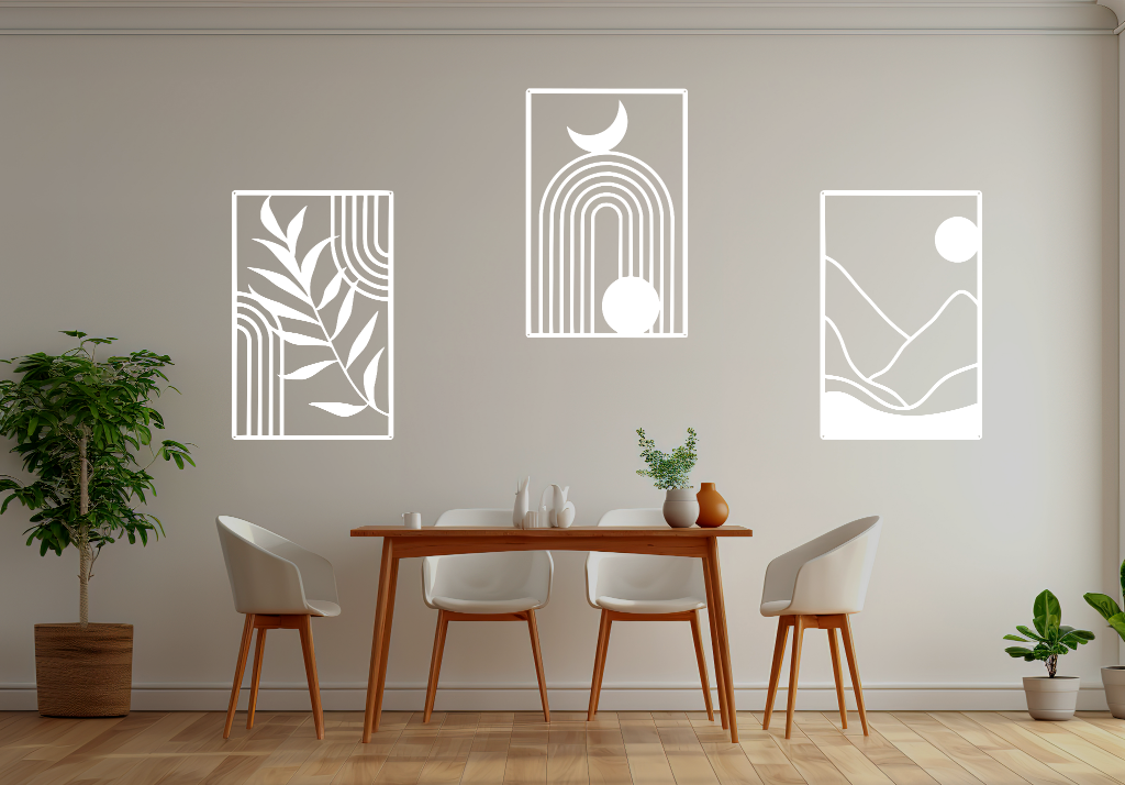 A three-piece minimalist geometric metal wall art set featuring abstract shapes, including a leaf design, a rainbow with moon and sun, and a mountain landscape, all finished in Bright White Gloss powder coating. The artwork is mounted on a dining room wall above a simple wooden table with white chairs, bringing a modern and artistic touch to the space.