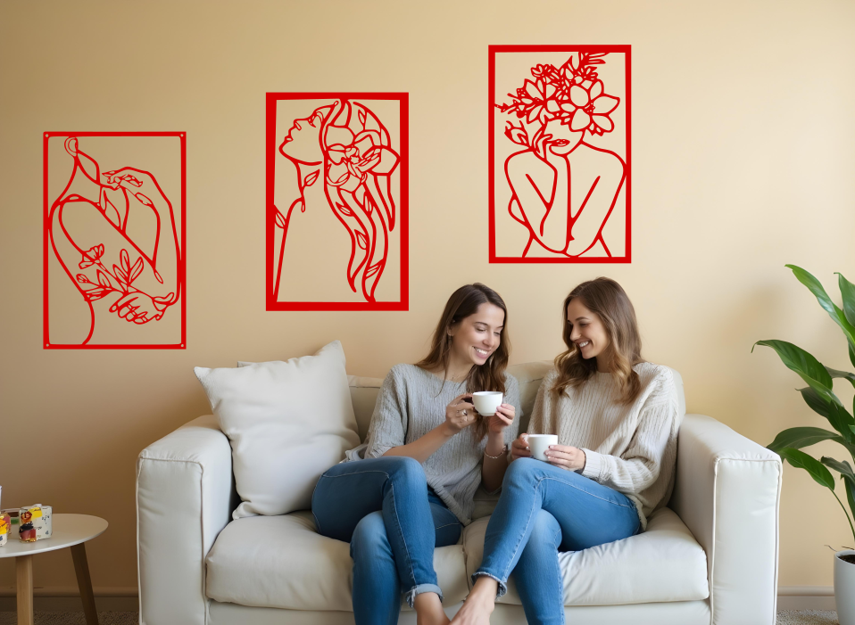 Set of three minimalist metal wall art pieces depicting floral-inspired female figures in various poses, finished in Signal Red powder coating, mounted on a neutral wall in a cozy living room setting where two women are enjoying coffee together.