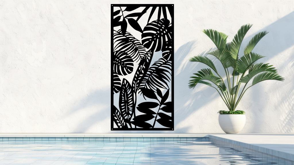 The 'Rainforest Leaves' metal privacy screen featuring an intricate design of tropical leaves, finished in Night Sky Matt Black powder coating. The screen is mounted on a white wall near a serene poolside area with a large potted plant, adding a bold and stylish touch to the outdoor space.