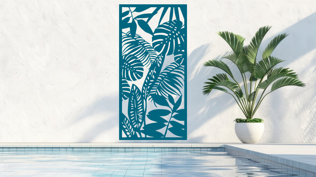 The 'Rainforest Leaves' metal privacy screen featuring an intricate design of tropical leaves, finished in Wedgwood Satin powder coating. The screen is mounted on a white wall near a serene poolside area with a large potted plant, adding a calming and stylish touch to the outdoor space